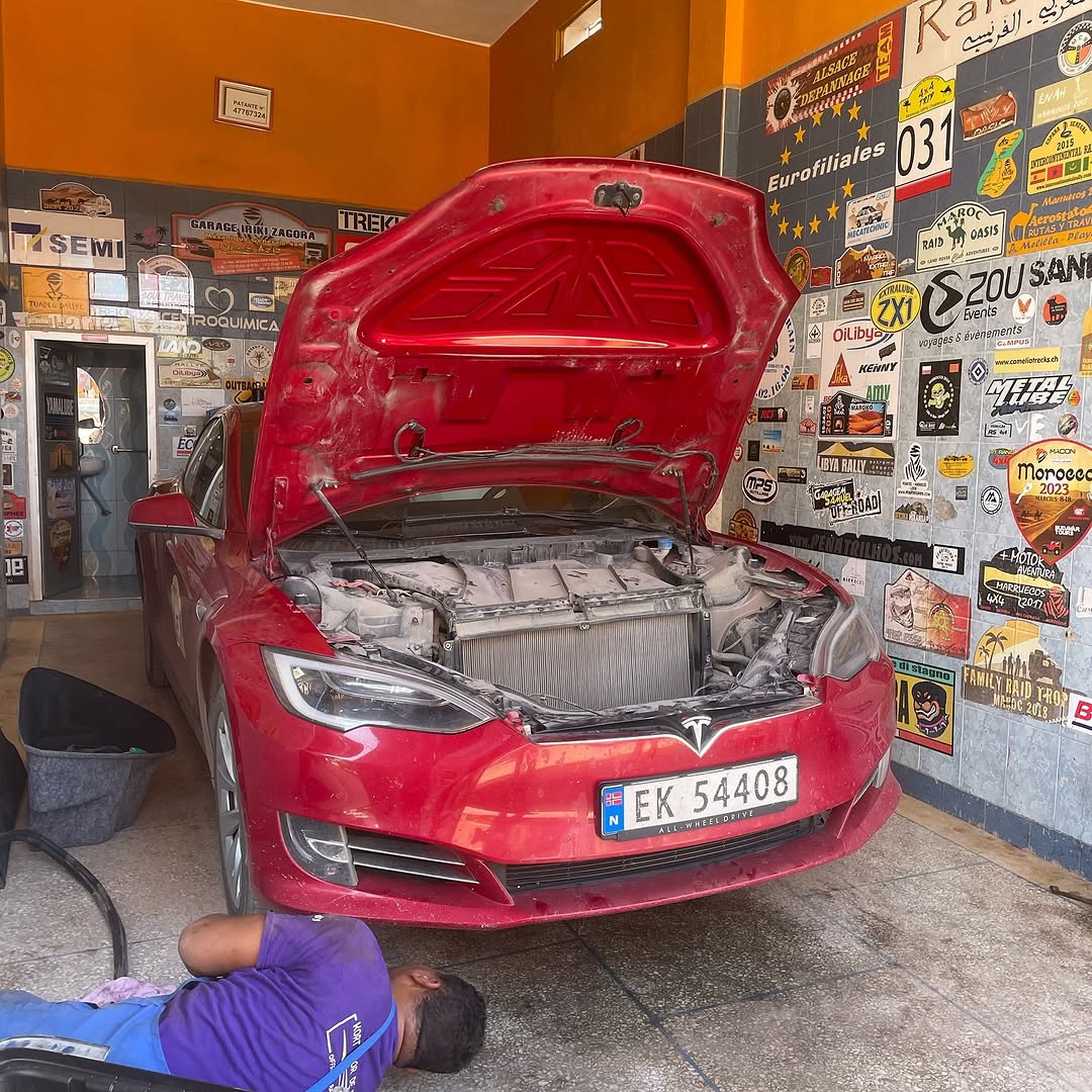 Red Tesla Model S with Norwegian plate EK 54408 up front at Garage Iriki Zagora, hood open and mechanic working underneath