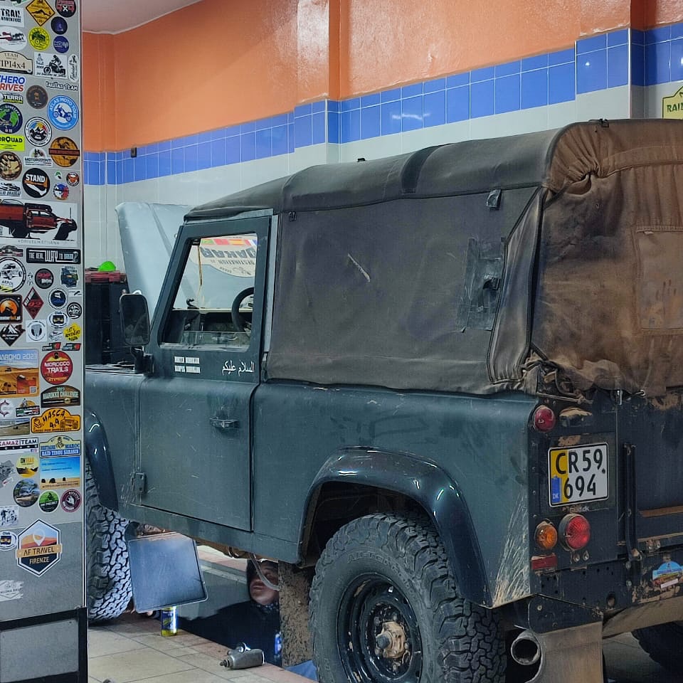 Rear view of the green Land Rover Defender 90 with Danish plate CR59694 inside Garage Iriki, Zagora