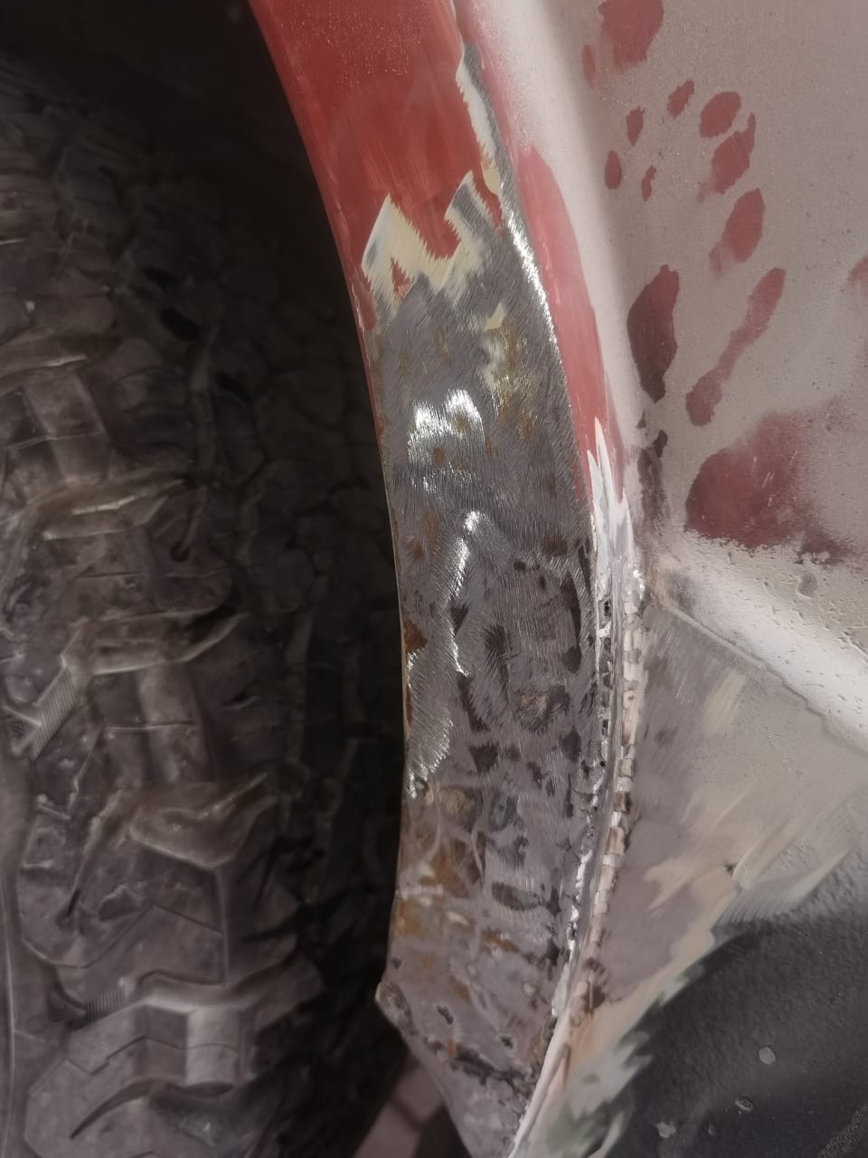 Ground-back wheel arch of the VW camper showing fresh welds and bare metal ready for primer