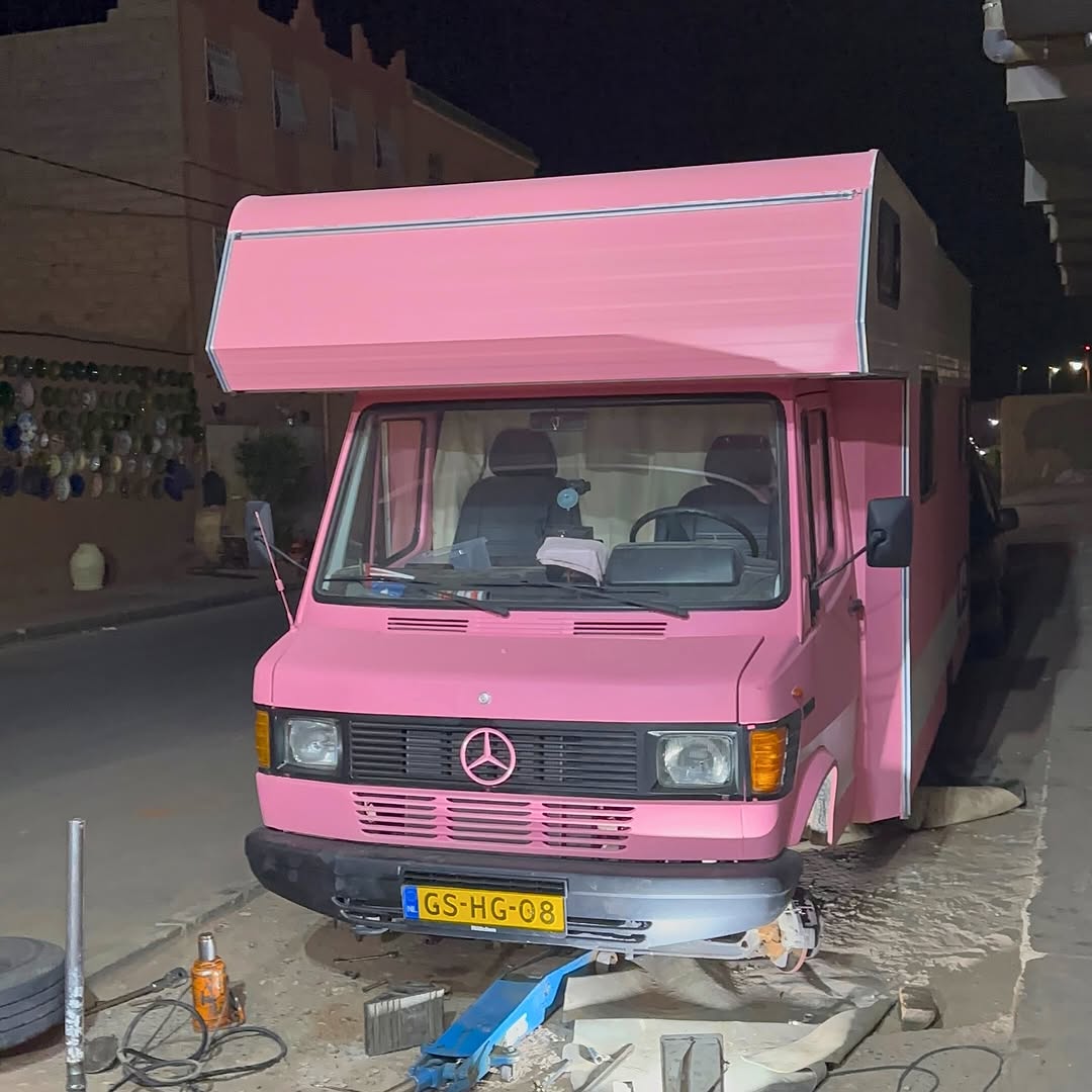 Mercedes 407D camper on hydraulic jack at night during front leaf spring installation at Garage Iriki, Zagora