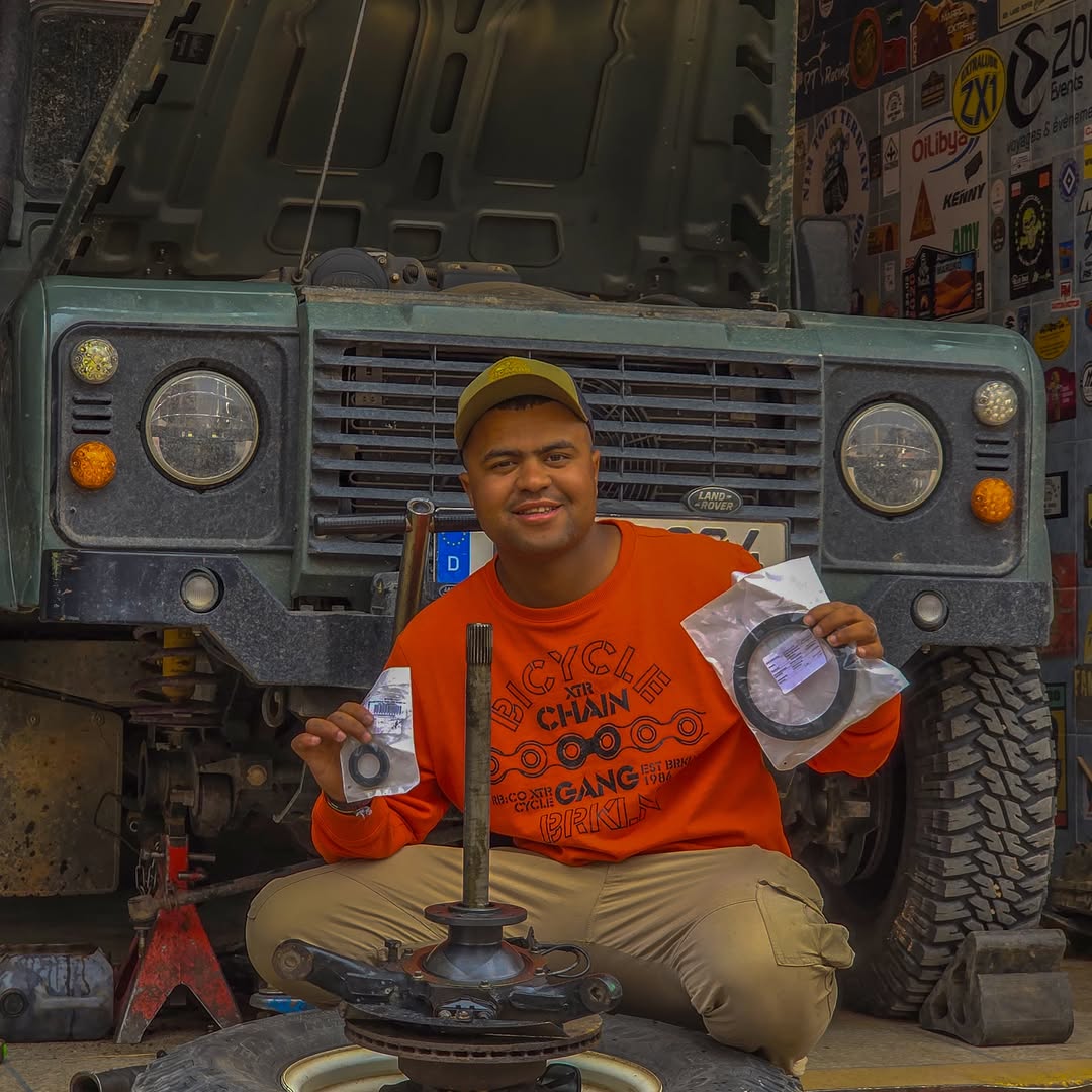 Zicaaaas mechanic Zakaria holding new swivel hub oil seals in front of the green Defender at Garage Iriki, Zagora